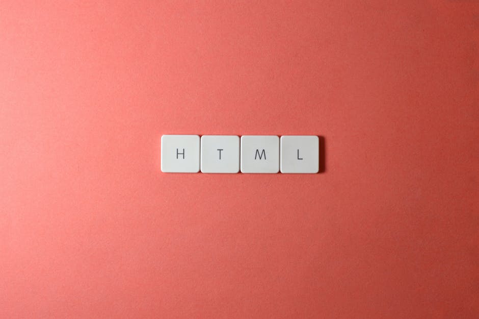 A close-up image showing four white square tiles with black letters spelling out 'HTML' arranged in a horizontal line on a smooth, pink background. The tiles are evenly spaced and uniform in size, wit