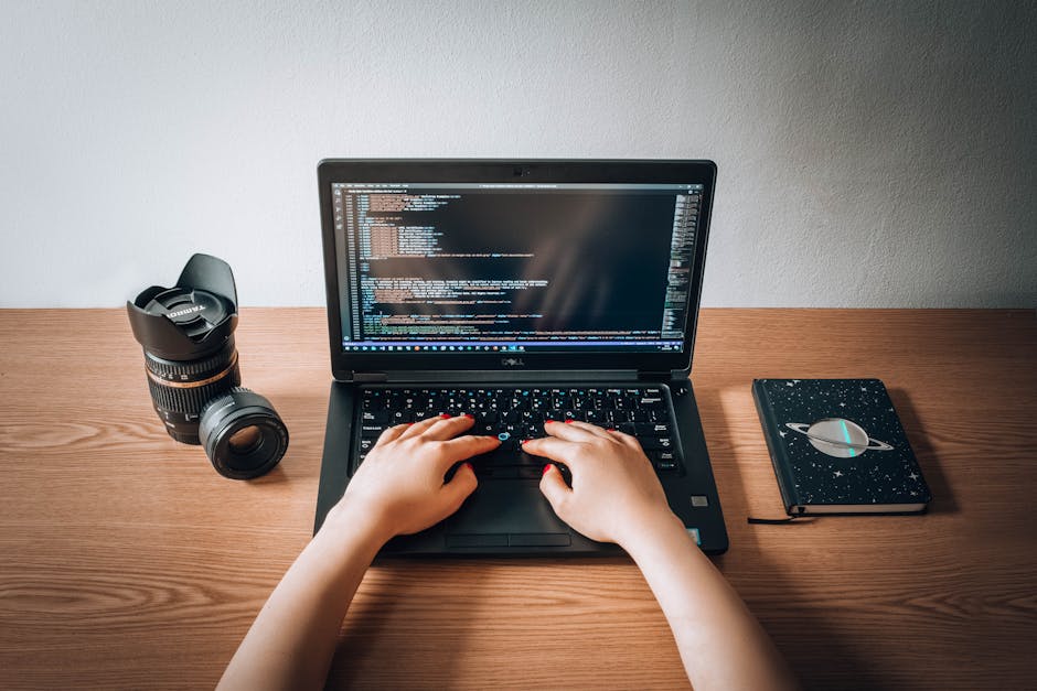 A laptop on a wooden desk displaying lines of code on a programming editor, with a ceramic coffee mug positioned to the right of the laptop. The mug features text that reads 'This Coffee is Making Me 
